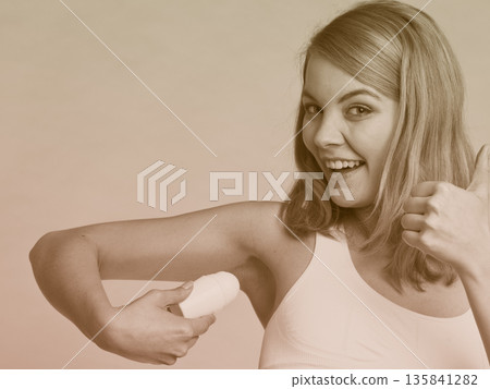 Girl applying stick deodorant in armpit. 135841282