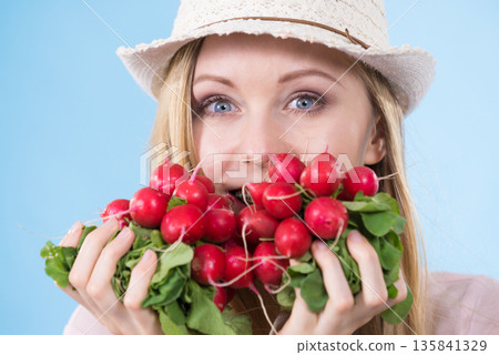 woman holding radish close to face woman holding radish close to face 135841329