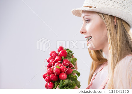 Young woman holding radish Young woman holding radish 135841330