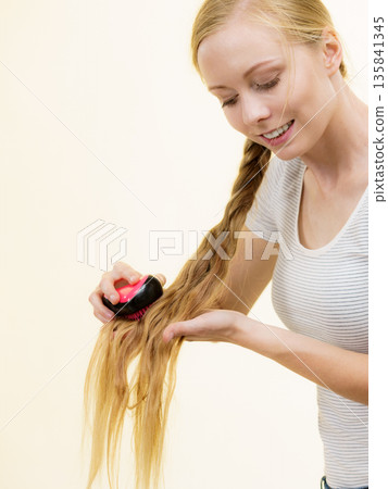 Blonde girl with long braid hair holds brush 135841345