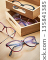 Variety of stylish eyeglasses in wooden organizer boxes on a wooden table 135841385