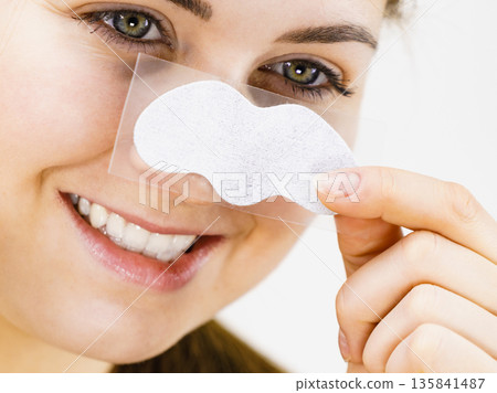 Woman applying pore strips on nose Woman applying pore strips on nose 135841487
