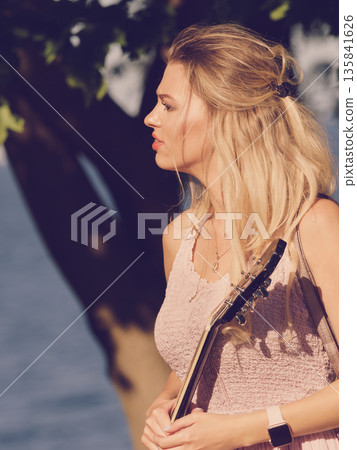 Woman playing acoustic guitar in park Woman playing acoustic guitar in park 135841626