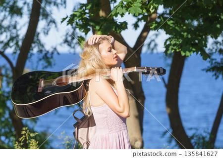 Woman playing acoustic guitar in park Woman playing acoustic guitar in park 135841627