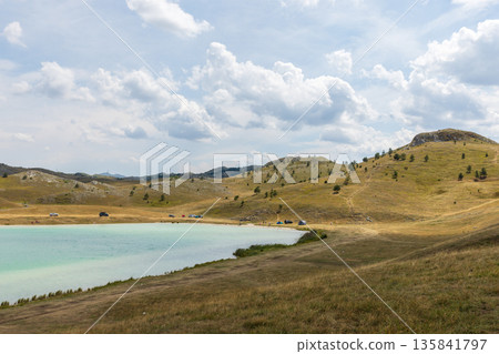 A tranquil countryside scene showing rolling golden hills and turquoise lake 135841797