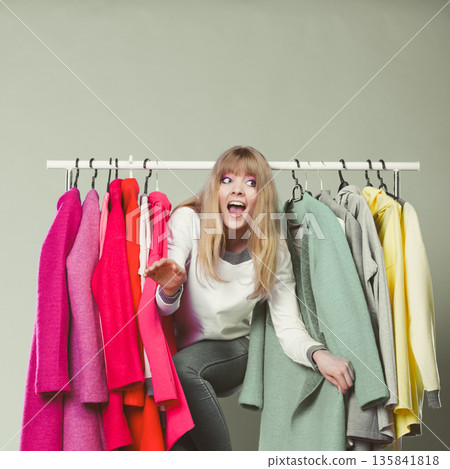Woman sneaking among clothes in mall or wardrobe. Woman sneaking among clothes in mall or wardrobe. 135841818
