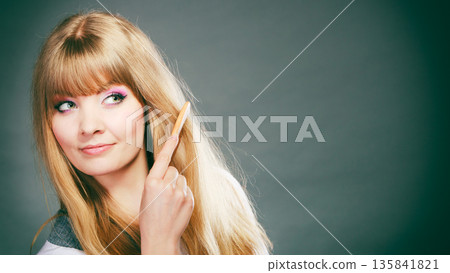 Woman combing her hair with comb 135841821