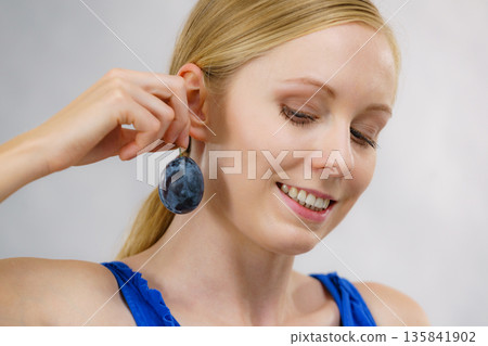 Girl holds plum fruit to her ear Girl holds plum fruit to her ear 135841902