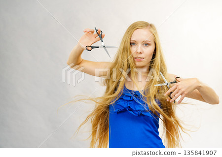 Young woman with scissors for haircutting 135841907