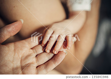 A baby's hand is being held by a woman's hand A baby's hand is being held by a woman's hand 135841946