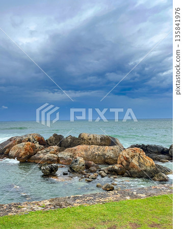 A rocky shoreline with a body of water in the background. 135841976