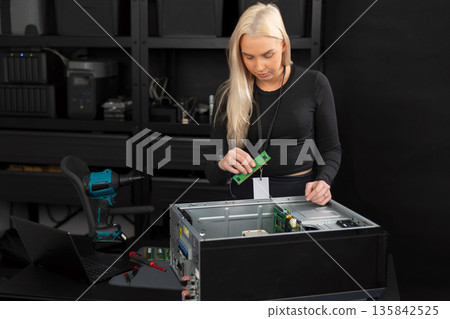 Female IT technician upgrades and maintains server hardware in a tech lab, performing diagnostics and repair 135842525