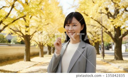 一位微笑的女子手捧一片銀杏葉 135842835