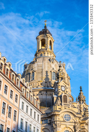 Frauenkirche stands tall in Dresden, Germany, showcasing its dome under a clear sky. Surrounding buildings add to the charm of this historic church during the Christmas festivities. Frauenkirche stands tall in Dresden, Germany, showcasing its dome under a clear sky. Surrounding buildings add to the charm of this historic church during the Christmas festivities. 135843332