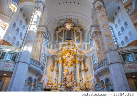 Visitors explore the interior of Frauenkirche in Dresden, Germany. The dome and ornate details showcase the church's architecture. Light filters through the windows, illuminating the space. 135843336