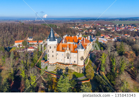 Aerial view of Zleby Castle showing its towers and rooftops. Surrounding area includes fields and small towns. The castle stands out in the landscape during clear weather. 135843343