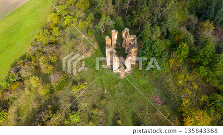 The drone view showcases the remnants of the Chapel of the Exaltation of the Holy Cross surrounded by lush greenery in Bristev. Nature reclaims history in the tranquil landscape. 135843368