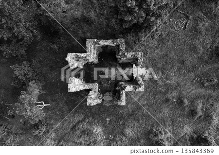 Drone view of the Chapel of the Exaltation of the Holy Cross in Bristev. The stone ruins contrast with the green landscape, revealing its historical significance and the passage of time. 135843369