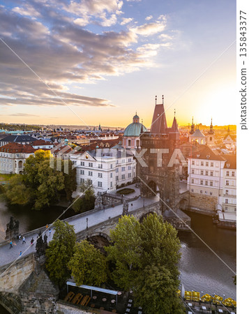 Sunset casts a warm glow on the Old Town Bridge Tower at Charles Bridge in Prague. The scenic view highlights the historic architecture and the Vltava River below, creating a charming atmosphere. Sunset casts a warm glow on the Old Town Bridge Tower at Charles Bridge in Prague. The scenic view highlights the historic architecture and the Vltava River below, creating a charming atmosphere. 135843377
