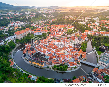 The dawn breaks over Cesky Krumlov, casting a warm glow on the medieval buildings and the winding Vltava River. This UNESCO World Heritage site is a picturesque town in Czechia. The dawn breaks over Cesky Krumlov, casting a warm glow on the medieval buildings and the winding Vltava River. This UNESCO World Heritage site is a picturesque town in Czechia. 135843414