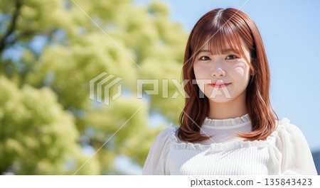 A woman smiling in a park with fresh green leaves A woman smiling in a park with fresh green leaves 135843423