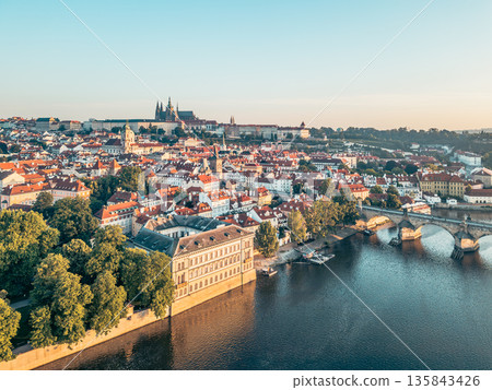 A breathtaking sunrise illuminates Prague's skyline, casting warm light over the medieval architecture and the Vltava River. A breathtaking sunrise illuminates Prague's skyline, casting warm light over the medieval architecture and the Vltava River. 135843426
