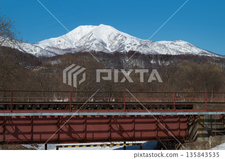 Railway bridge near Konbu Station in late winter and snowy scenery of Niseko Annupuri in winter Railway bridge near Konbu Station in late winter and snowy scenery of Niseko Annupuri in winter 135843535