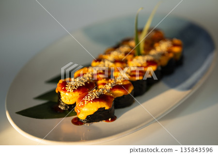Baked sushi rolls topped with melted cheese sauce, teriyaki and sesame seeds 135843596