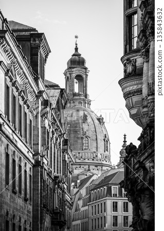 Frauenkirche rises above the buildings in Dresden. The dome is a prominent feature of the church and attracts visitors during the Christmas season. Streets are quiet in the winter light. Frauenkirche rises above the buildings in Dresden. The dome is a prominent feature of the church and attracts visitors during the Christmas season. Streets are quiet in the winter light. 135843632