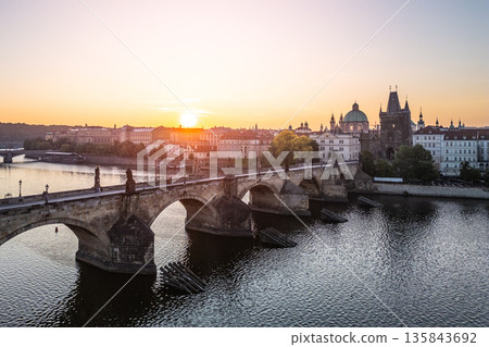 Golden sunlight illuminates Charles Bridge in Prague at dawn. The iconic structure stands gracefully over the Vltava River, creating a stunning urban panorama without crowds. Golden sunlight illuminates Charles Bridge in Prague at dawn. The iconic structure stands gracefully over the Vltava River, creating a stunning urban panorama without crowds. 135843692