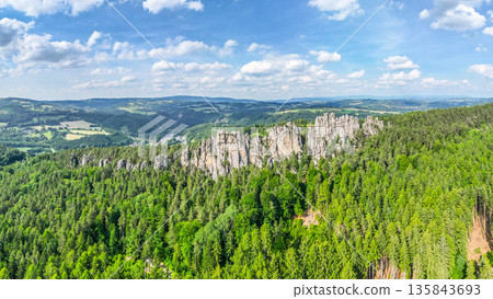 Explore the stunning sandstone formations of Suche skaly in Bohemian Paradise, surrounded by lush forests and rolling hills under a bright blue sky. Explore the stunning sandstone formations of Suche skaly in Bohemian Paradise, surrounded by lush forests and rolling hills under a bright blue sky. 135843693