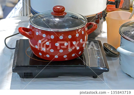 Red pot on stove Red pot on stove 135843719