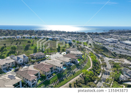 Aerial view over San Juan Capistrano, California, featuring the historic mission, library, sports courts, and an Amtrak train pulling into the downtown station. 135843873
