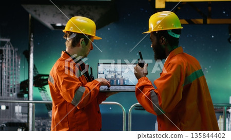 Offshore engineers communicate via walkie talkie at night on oil platform under the aurora borealis, ensuring oil and gas emission tracking and safe drilling rig operations. Offshore engineers communicate via walkie talkie at night on oil platform under the aurora borealis, ensuring oil and gas emission tracking and safe drilling rig operations. 135844402