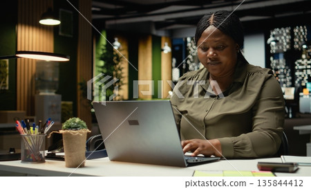 Distressed troubled worker struggling with mental exhaustion and discomfort late at night, showing signs of intense workload and unhealthy lifestyle. Overwhelmed woman with anxiety. Camera A. Distressed troubled worker struggling with mental exhaustion and discomfort late at night, showing signs of intense workload and unhealthy lifestyle. Overwhelmed woman with anxiety. Camera A. 135844412