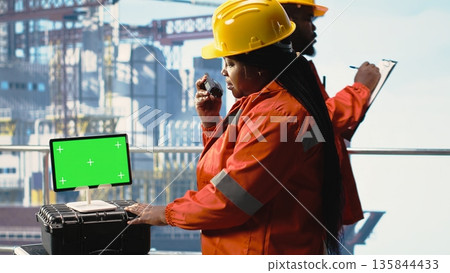 Isolated screen tablet used by drilling rig expert to monitor systems, talking in handheld radio. Offshore platform technician using walkie talkie, calibrating gear with chroma key device Isolated screen tablet used by drilling rig expert to monitor systems, talking in handheld radio. Offshore platform technician using walkie talkie, calibrating gear with chroma key device 135844433