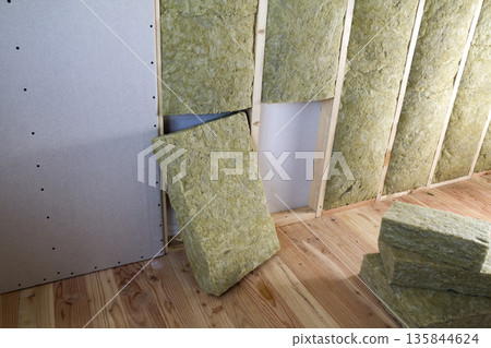 Wooden frame for future walls with drywall plates insulated with rock wool and fiberglass insulation staff for cold barrier. Comfortable warm home, economy, construction and renovation concept. 135844624