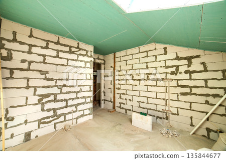 Interior of an apartment room with bare walls and ceiling under construction. Interior of an apartment room with bare walls and ceiling under construction. 135844677