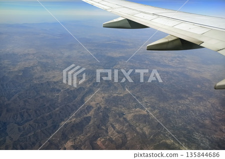 View through airplane window of commercial jet plane wing flying high in the sky. Air travelling concept 135844686
