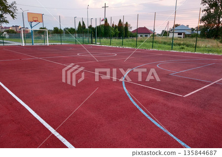 Outdoors mini football and basketball court with ball gate and basket surrounded with high protective fence. 135844687