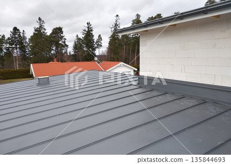 Close-up detail of house roof made from gray metal sheets. 135844693