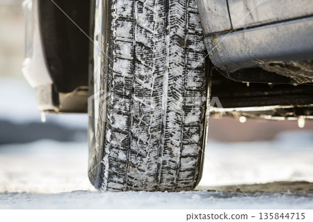 Close-up of car wheels rubber tire in deep snow. Transportation and safety concept. Close-up of car wheels rubber tire in deep snow. Transportation and safety concept. 135844715