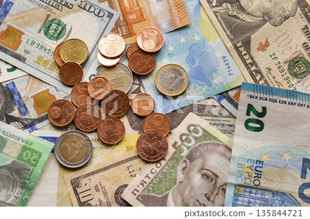 Colorful abstract background made of different metal coins, American, Ukrainian bills and euro banknotes currency. Money and finances, successful investment concept. Colorful abstract background made of different metal coins, American, Ukrainian bills and euro banknotes currency. Money and finances, successful investment concept. 135844721