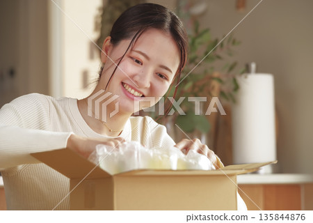 A Japanese woman looks happy after opening her package A Japanese woman looks happy after opening her package 135844876