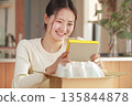 A Japanese woman looks happy after opening her package 135844878