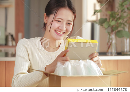 A Japanese woman looks happy after opening her package 135844878