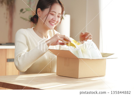 A Japanese woman looks happy after opening her package A Japanese woman looks happy after opening her package 135844882