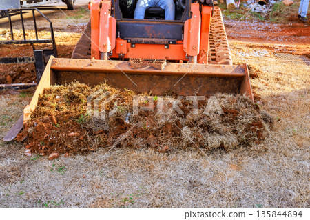 Tractor works on yard, pushing dirt grass near construction site. Tractor works on yard, pushing dirt grass near construction site. 135844894