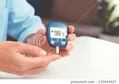 Man measures his blood sugar level 135844927