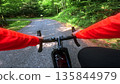 POV road cycling on forest mountain road following another cyclist 135844979